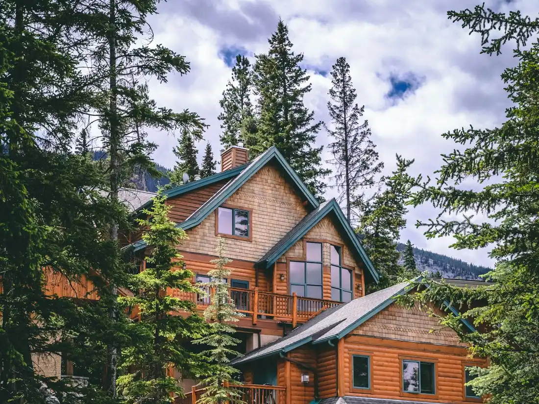 A timber family home with a stone garage among evergreens