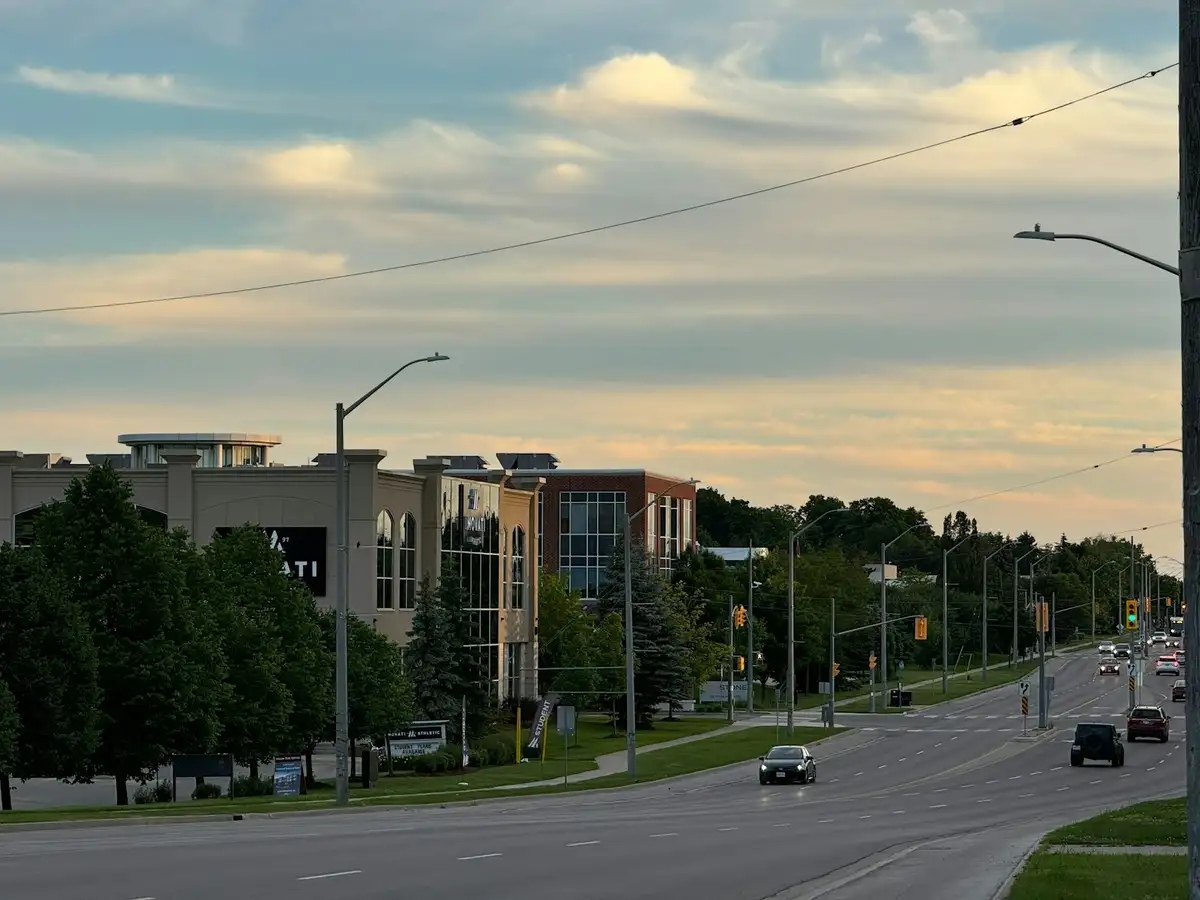 A Guelph street at dusk with a commercial building and passing cars