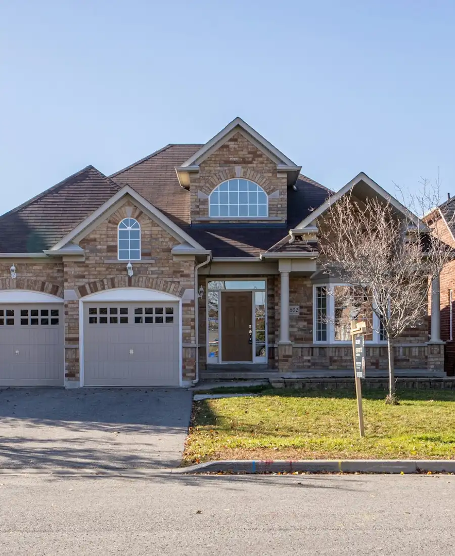 Stone two-storey home with a double garage and a maple out front